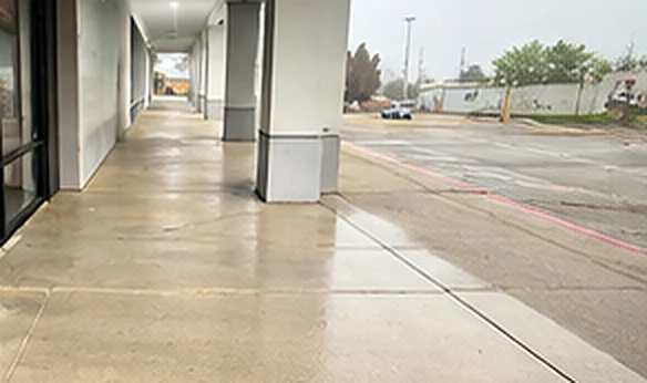 Storefront sidewalk after pressure washing by Divine