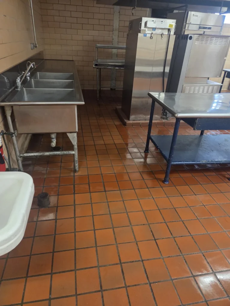Clean quarry tile floor and stainless steel sinks in a commercial kitchen after service by Divine Cleaning and Janitorial