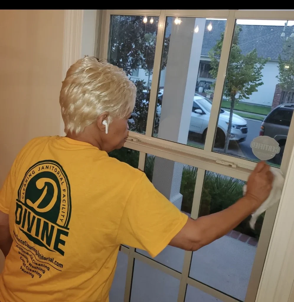Divine Cleaning and Janitorial team member cleaning window panes from inside an office