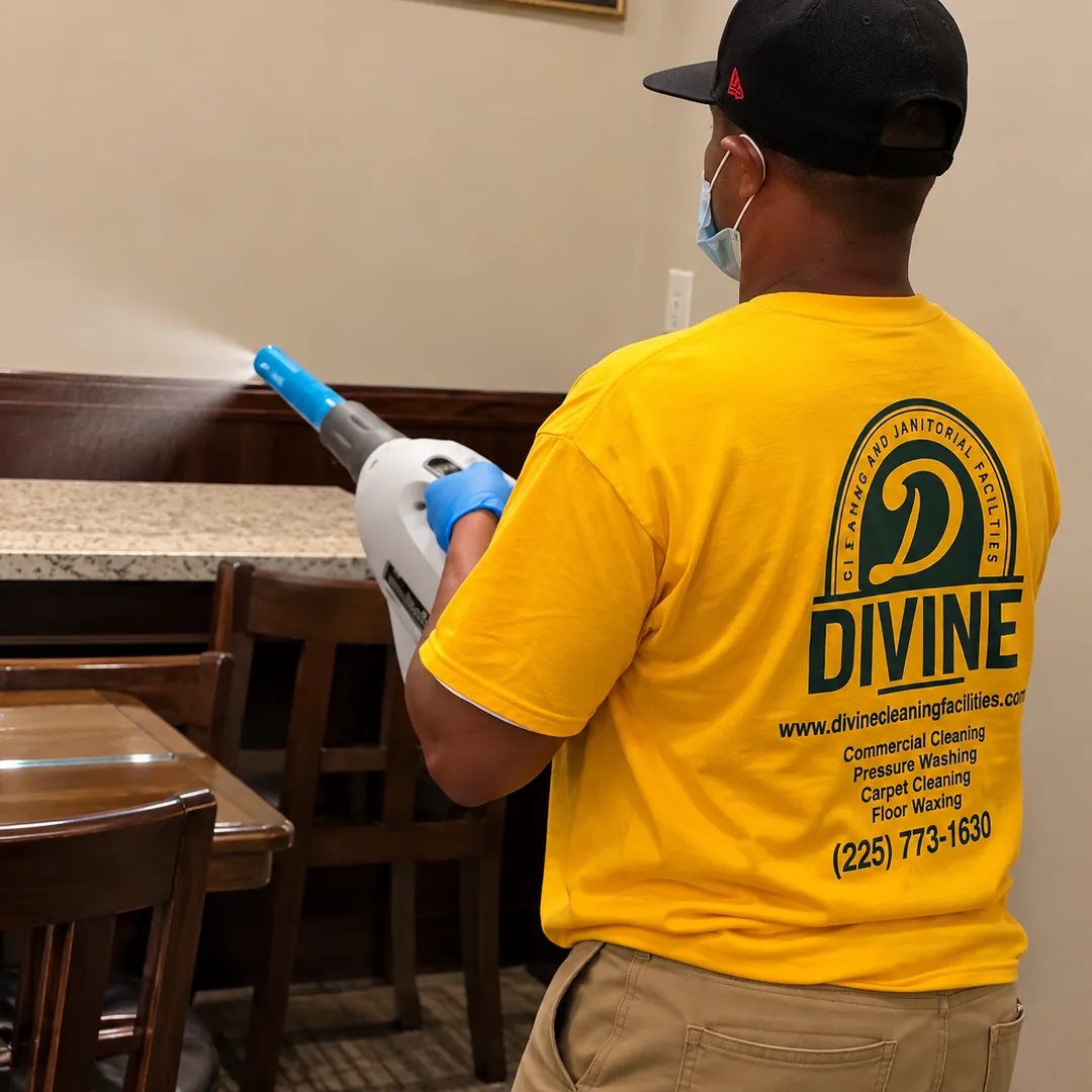 Divine Cleaning and Janitorial team member using an electrostatic sprayer to disinfect tables and chairs
